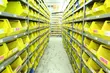 Long aisle between tall shelving units filled with yellow storage bins in an organized warehouse or inventory facility.